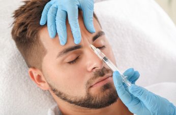 Handsome man receiving filler injection in beauty salon