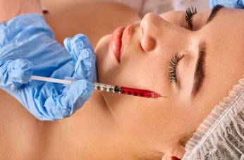 Close-up of a patient receiving an aesthetic under-eye treatment with a precision syringe. A professional wearing blue gloves performs the procedure for facial rejuvenation and dark circle correction.