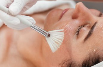 esthetician applying chemical peel solution to womans face during spa treatment