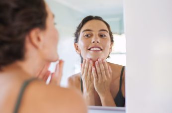 woman checking glowing skin in mirror after chemical peel aftercare