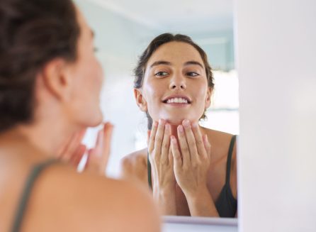 woman checking glowing skin in mirror after chemical peel aftercare